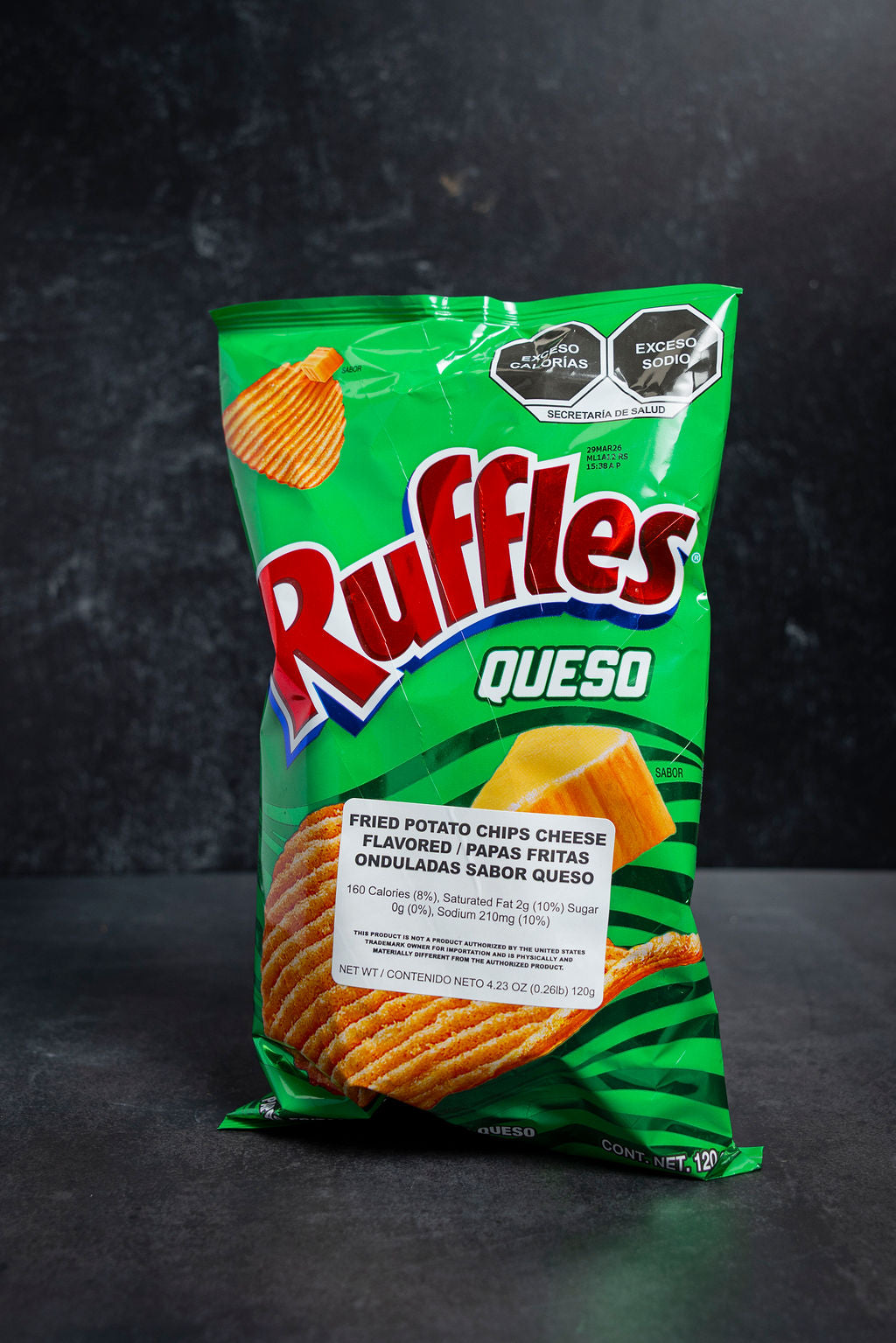 Green Ruffles Queso potato chip bag on a dark background