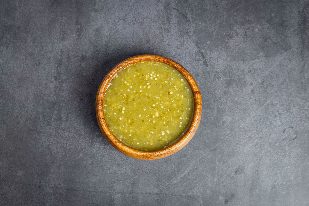 Green sauce in a wooden bowl on a gray background