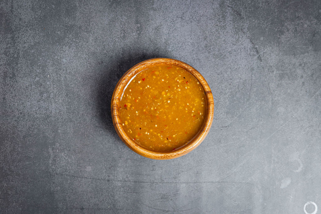 Wooden bowl with a brown sauce on a gray surface