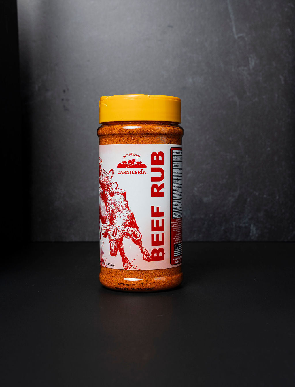 Jar of beef rub with a yellow lid on a dark background
