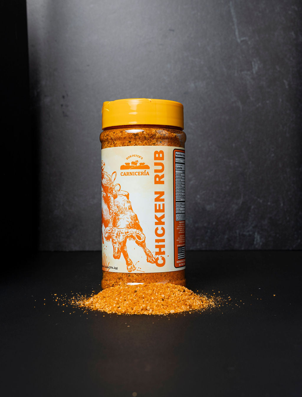Bottle of chicken rub with a yellow lid on a dark background