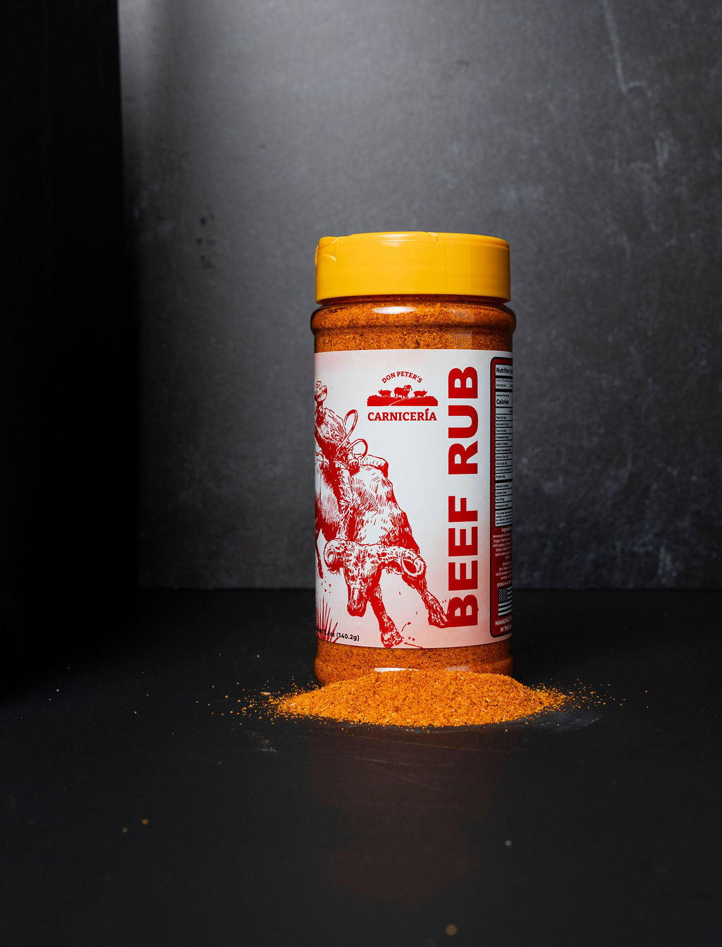 Jar of beef rub with a yellow lid on a dark background