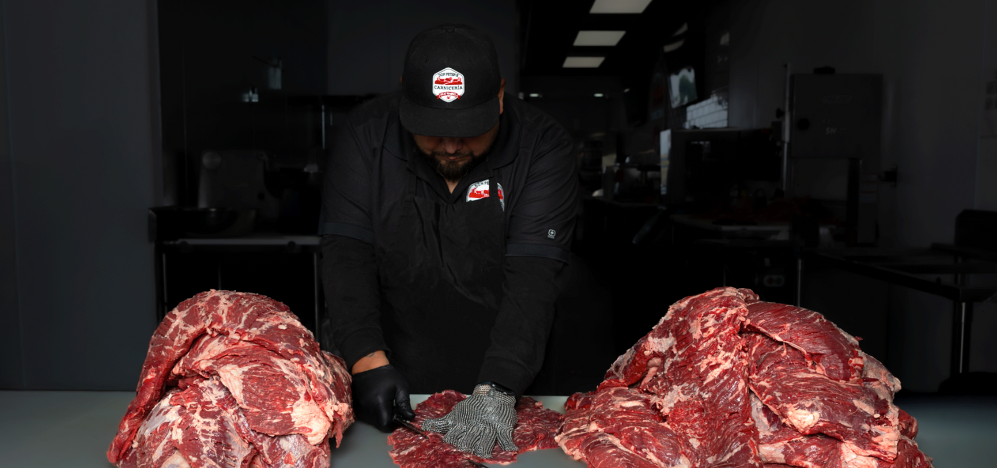 different cuts of raw meat lined up with herbs and knives