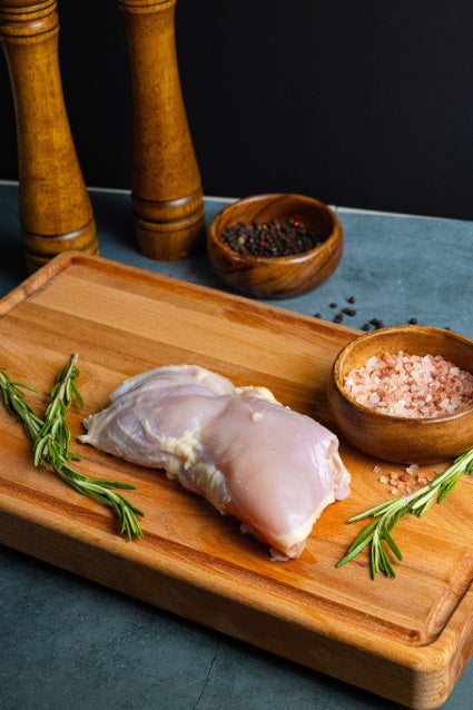 chicken thighs on a cutting board next to salt and rosemary